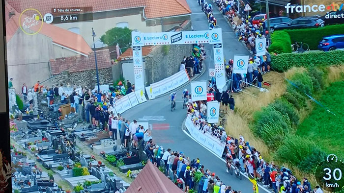 Tour de France fans standing on graves for better view near race route, sparking outrage among spectators and community.