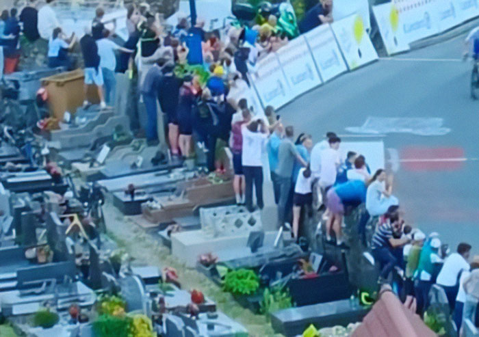 Tour De France fans standing on graves to get a better view, sparking outrage among spectators and communities.
