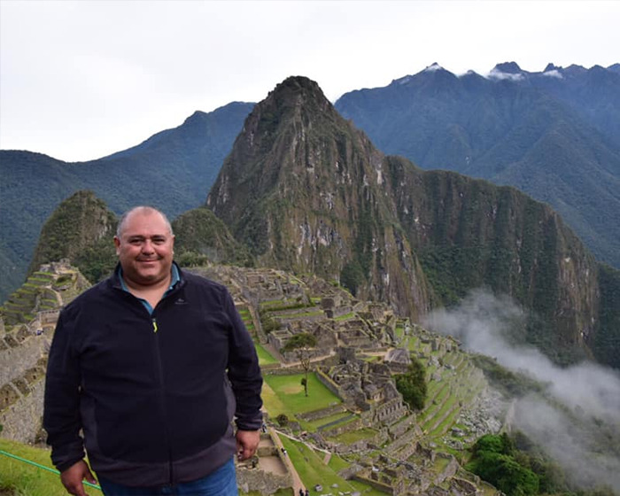 Tourist posing at a mountain site with scenic view, unrelated to bear drags tourist off cliff incident.