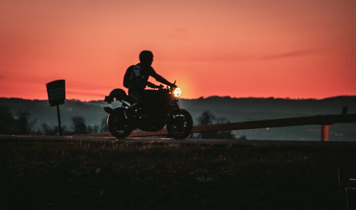 Silhouette of a person riding a motorcycle at sunset, illustrating a gut feeling that saved them from danger.