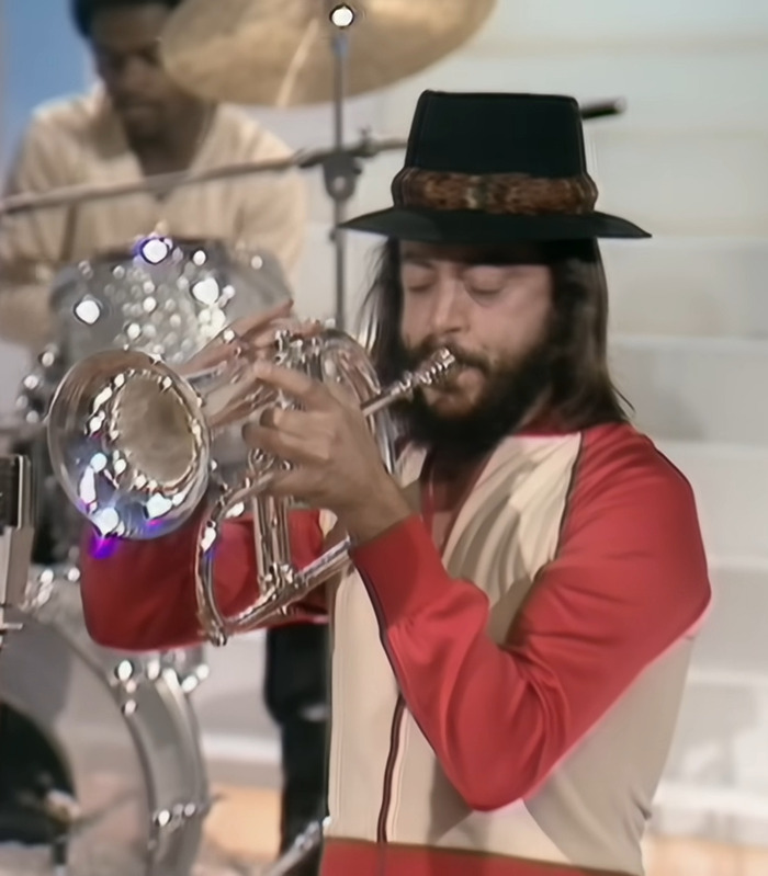 Jazz musician playing trumpet passionately during live performance with drummer in the background, showcasing legendary jazz music. - 6