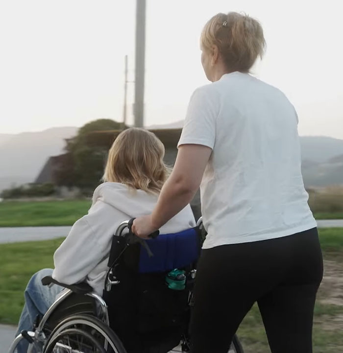 Person pushing wheelchair outdoors, representing model found with broken limbs and spine on Dubai roadside. - 10