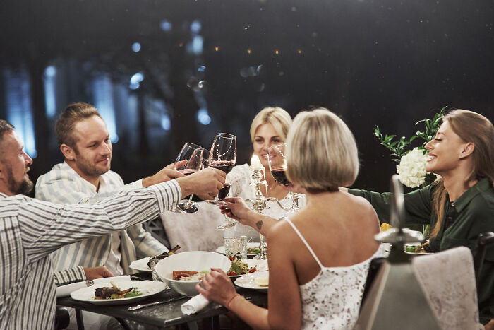 Group of people toasting with wine glasses at a wedding dinner, capturing a moment with an unhinged family member present. - 26