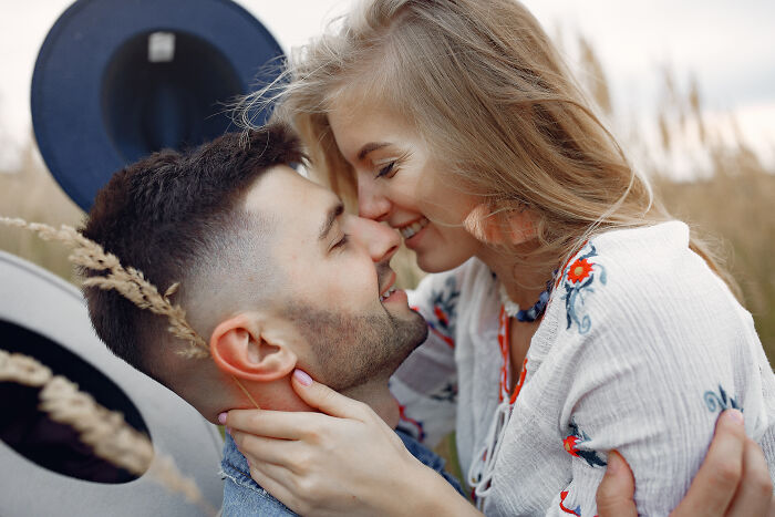 Couple embracing closely in a field, showing affection despite an unhinged family member at the wedding event. - 34