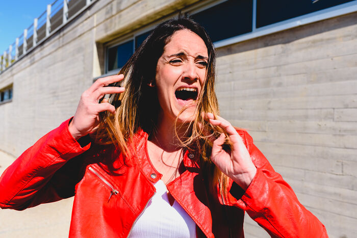 Woman wearing red jacket reacting emotionally outdoors, depicting an unhinged family member at a wedding event. - 9