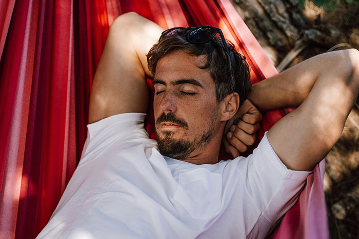 Man relaxing peacefully in a hammock outdoors, illustrating life hacks that improve life quality and wellbeing.