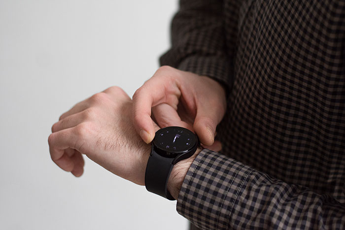 Person adjusting a black smartwatch on wrist, demonstrating life hacks that improve daily life quality and efficiency.