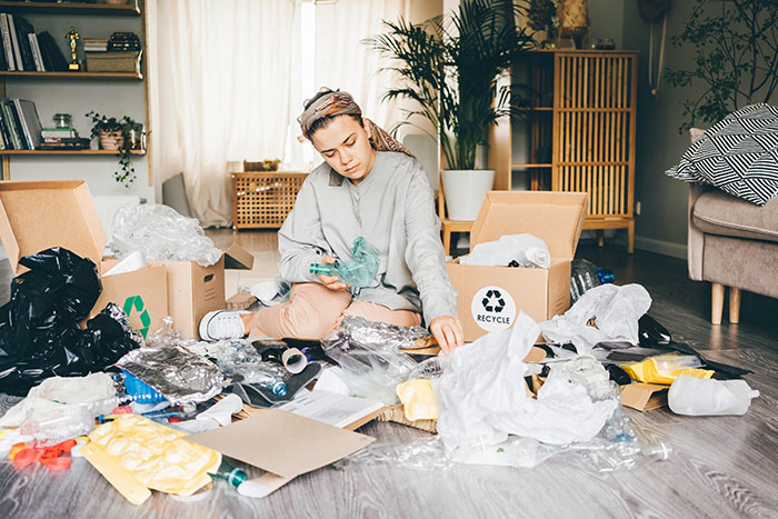 A woman sorting recyclable waste at home, demonstrating life hacks that actually work to improve life quality.