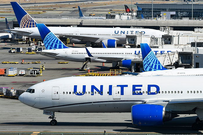 Multiple United Airlines planes parked at the airport tarmac near terminals on a sunny day