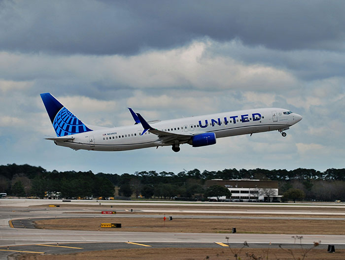 United Airlines plane taking off under cloudy sky, related to trafficking accusations by airline crew.