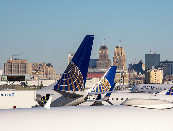 United Airlines planes parked at the airport with city skyline in the background during clear daylight hours.