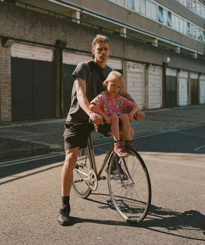 Man with a young girl on a bike in a London street, capturing honest photos of everyday life by Nico Froehlich.