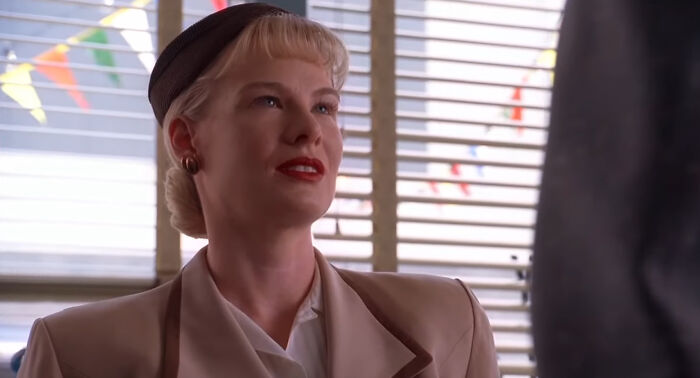 Woman with vintage hairstyle and attire sitting in a brightly lit room from shows with characters hard to love - 31