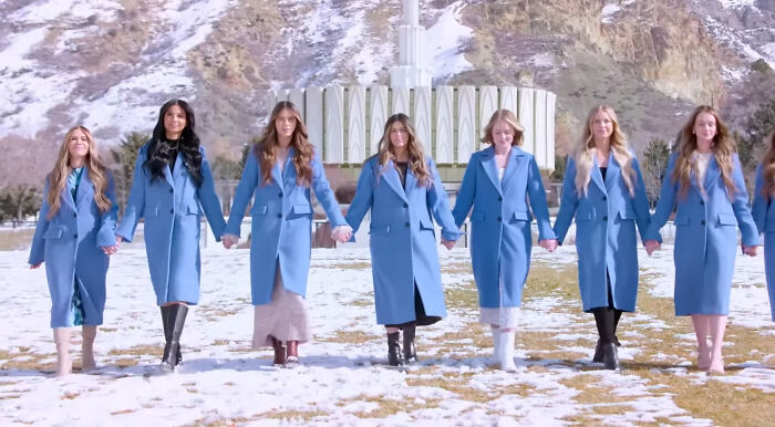 Group of women in matching blue coats holding hands outdoors with snowy mountains, representing shows with hard to love characters - 11
