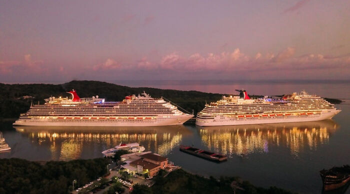 Two large cruise ships docked near a tropical shore at sunset, highlighting a popular vacation destination poll.