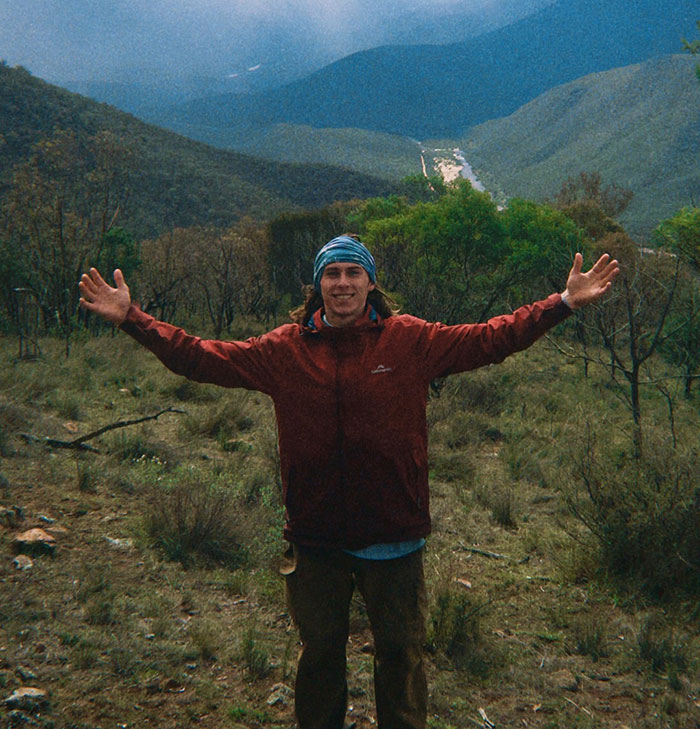 21YO daredevil in a red jacket standing with arms outstretched in a mountainous outdoor setting before record-breaking dive footage