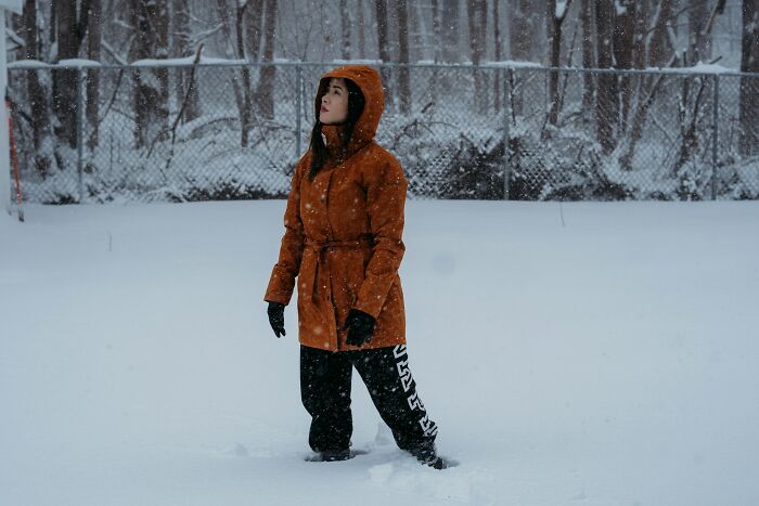 Person wearing an orange jacket and black gloves standing in deep snow, illustrating entitled patients demanding special treatment.