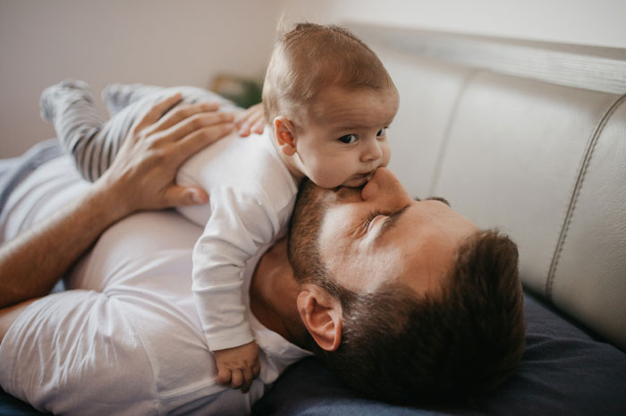 Baby boy lying on father's chest in cozy home setting, representing very rare boy names for stand-out babies.