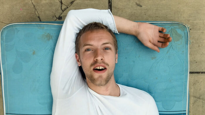 Young man lying on a blue cushion outdoors, expressing surprise, illustrating emotions tied to celebrities people can't stand.