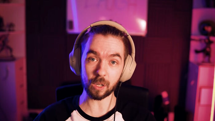 Man wearing headphones speaking in a dimly lit room, illustrating people share unsubscribed YouTubers concept.