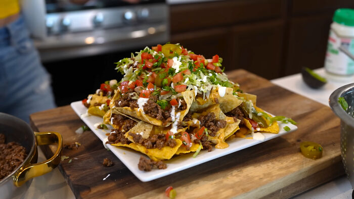 Plate of loaded nachos with meat, cheese, and toppings illustrating trends leading to overconsumption in food culture. - 11