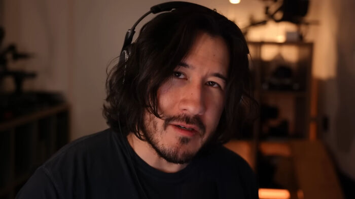 Man wearing headphones in a dimly lit room, representing people share unsubscribed YouTubers discussing content online.