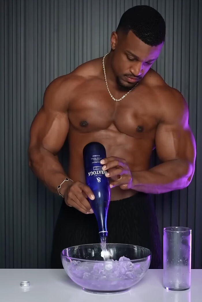 Muscular man pouring liquor into an ice-filled bowl, illustrating trends contributing to overconsumption concerns. - 26