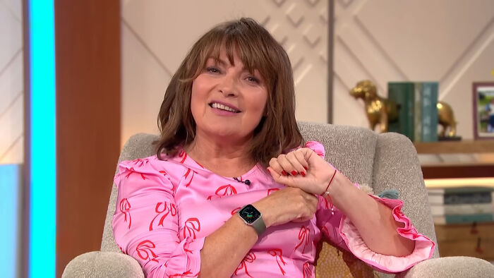 Woman in a pink blouse sitting on a chair, smiling during a talk about celebrities many people love but can't stand.