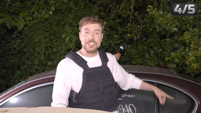 A man wearing a black tactical vest speaking outdoors beside a car, illustrating people share unsubscribed YouTubers.