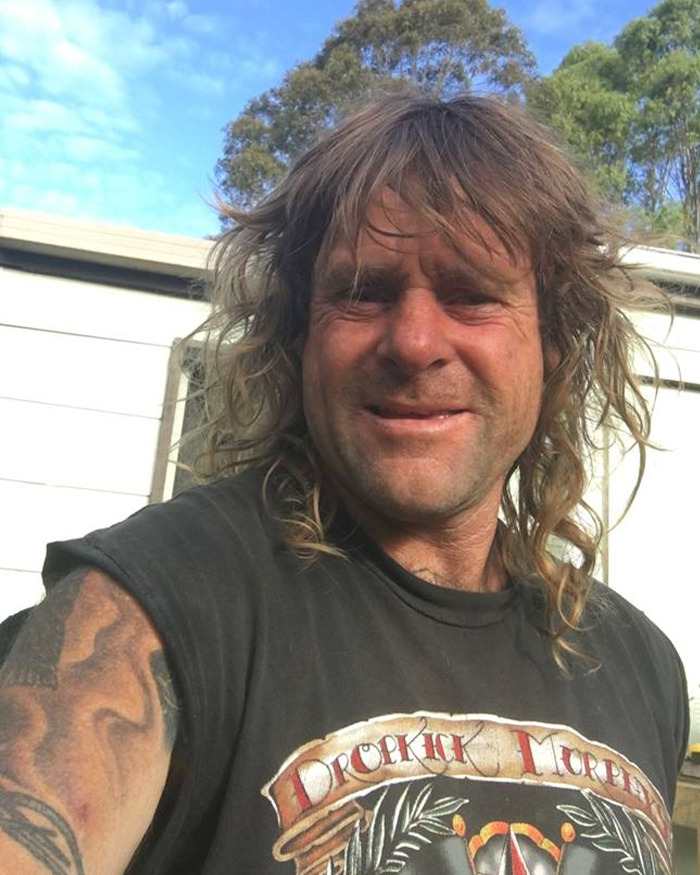 Man with long hair and tattoos outdoors, related to vigilante who punished and executed an innocent dad wrongly accused of assault. - 1