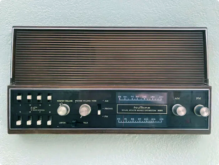 Vintage wall-mounted NuTone AM FM radio with manual tuning and volume controls, a classic vintage thing from past decades
