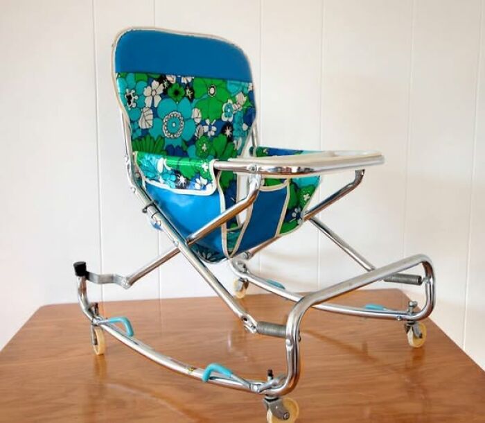 Vintage floral baby stroller with bright blue and green fabric and chrome frame on wooden floor, showcasing vintage things.