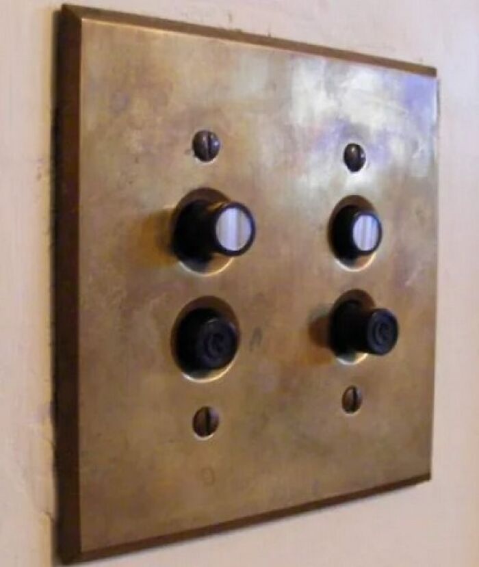 Vintage things metal light switch plate with unique black rotary and push-button controls on a wall close-up