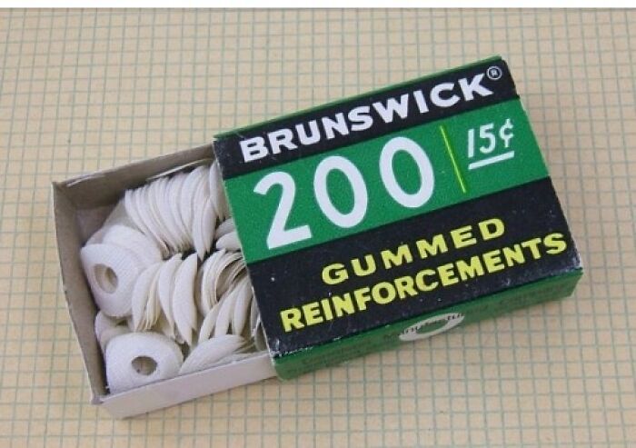 Box of vintage Brunswick gummed reinforcements for paper holes, showcasing nostalgic office supplies from past decades.