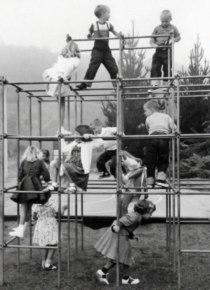 Children playing on a vintage metal jungle gym in a schoolyard, showcasing classic playground equipment and vintage things.