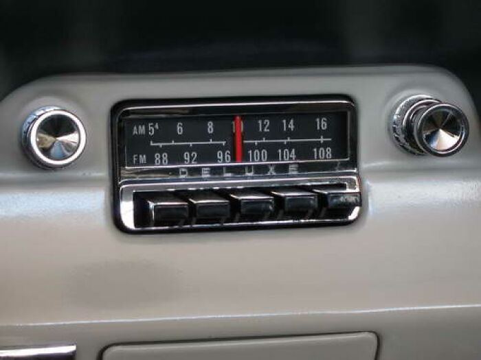 Vintage car radio dial and knobs showing classic analog tuning with push buttons and chrome details from a retro vehicle dashboard.