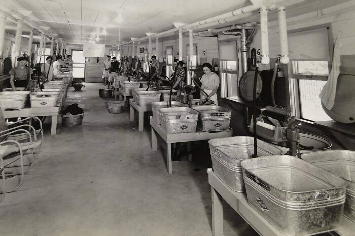 Black and white photo of a vintage laundry facility with metal tubs and workers, showcasing vintage things.