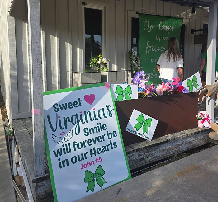Memorial signs and flowers honoring a young girl after Camp Mystic tragedy with green ribbon awareness symbols. - 8