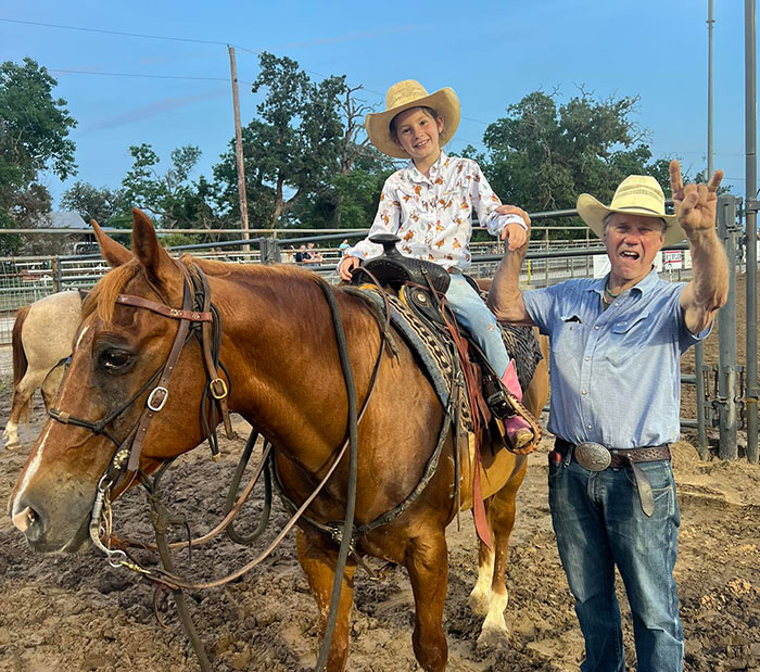 Young girl in cowboy hat riding horse next to man in hat, highlighting 8-year-old’s horse after Camp Mystic tragedy. - 6
