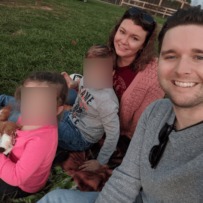 Virginia councilman outdoors with family, smiling and sitting on grass during a casual evening gathering.