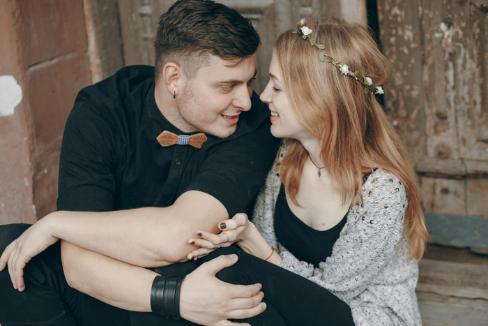 Young couple sitting closely, smiling and looking at each other, highlighting woman set to marry guy after conflict.