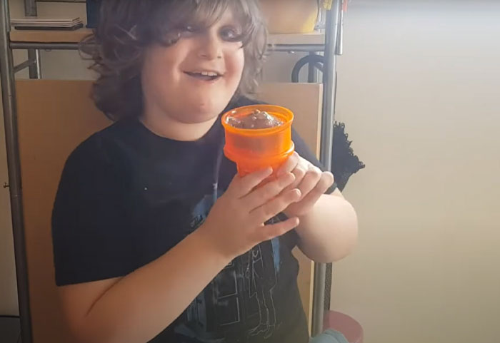 Child holding a small orange weird invention with a smile, showcasing unusual inventions the world wasn’t prepared for.