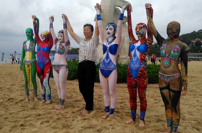 Group of people with body paint in animal and mask designs on a beach, showcasing some of the weird inventions.