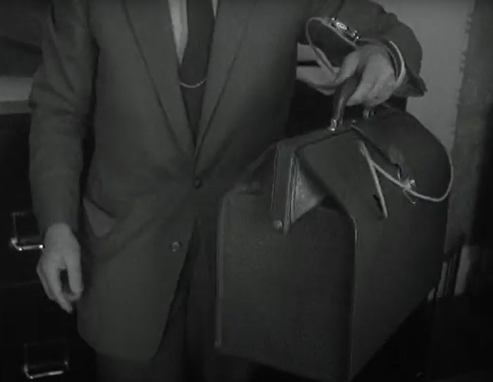 Man in suit holding unusual vintage briefcase with a strange handle, one of the weird inventions not expected by the world