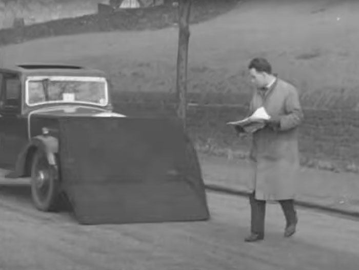 A man examines an old car with a large unusual ramp attachment, showcasing one of the weird inventions.