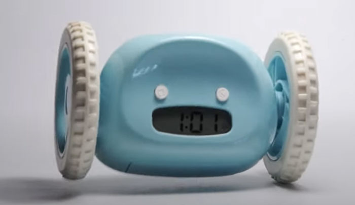 Blue clock with wheels on both sides designed as a weird invention to make waking up more challenging and active.