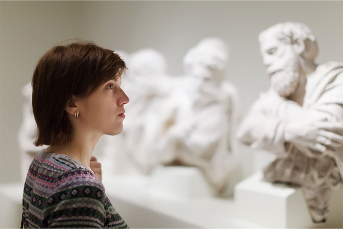 Woman observing classical busts in museum, reflecting on things non-Americans find weird about the US that locals see as normal. - 35