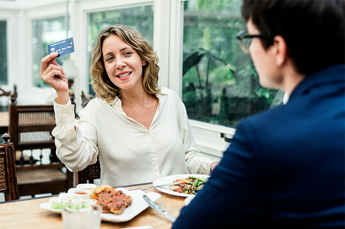 Woman showing credit card during a meal, illustrating things non-Americans find weird about the US culture. - 21