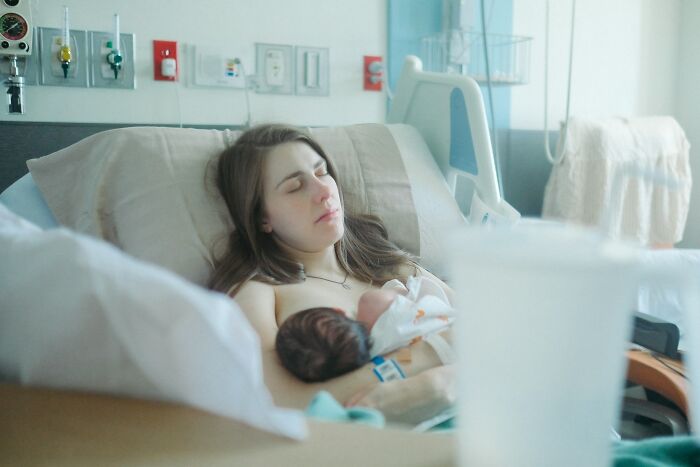 Mother resting in hospital bed holding newborn baby, illustrating common experiences after birth and postpartum challenges.