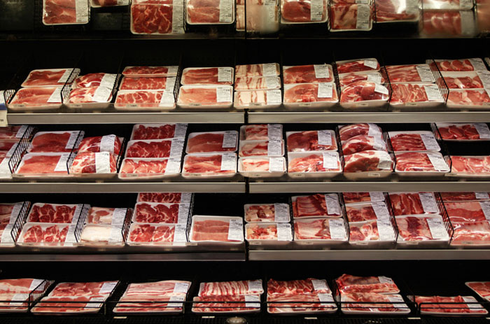 Packaged American meats displayed on supermarket shelves highlighting foods banned in other countries.